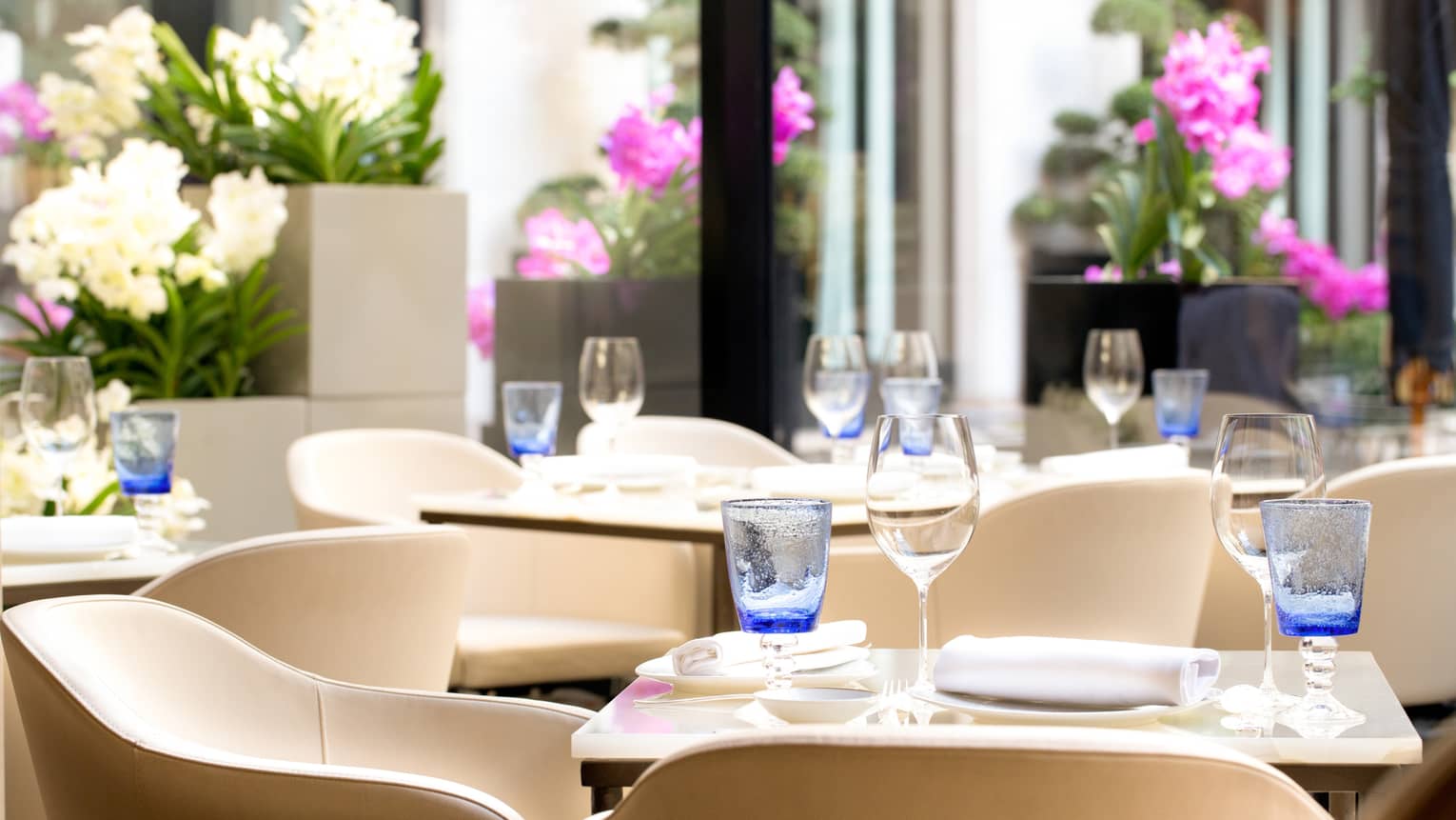 Le George dining room, white chairs around tables, blue glasses, purple flowers