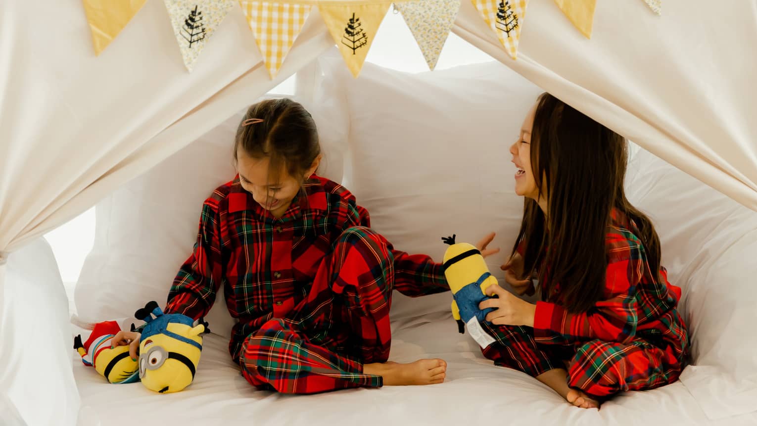 Two young girls in pajamas playing with stuffed animals.