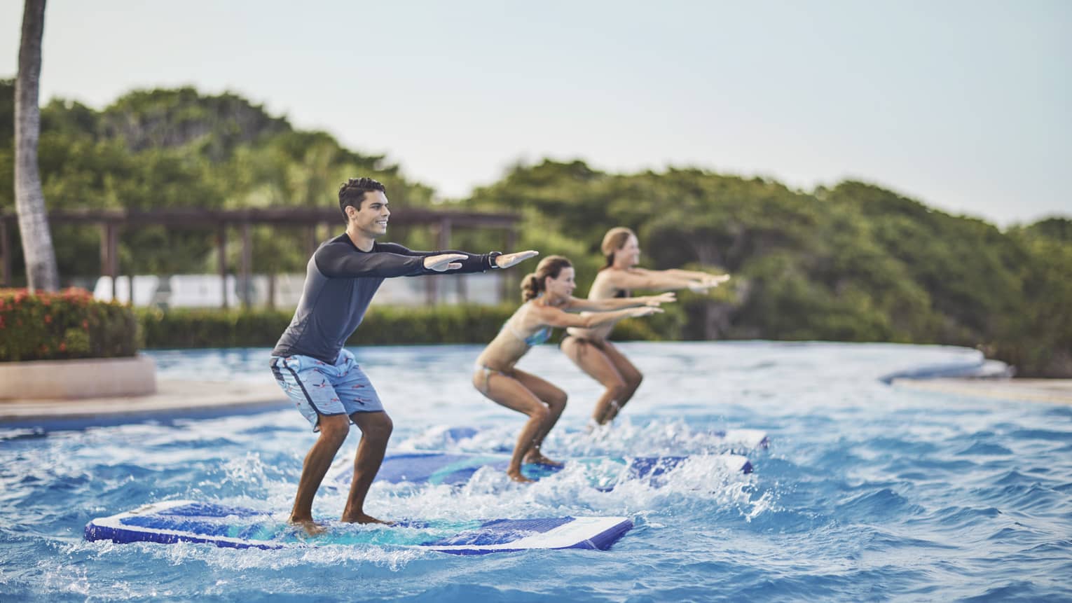 Two guests being instructed how to stand up on surf boards