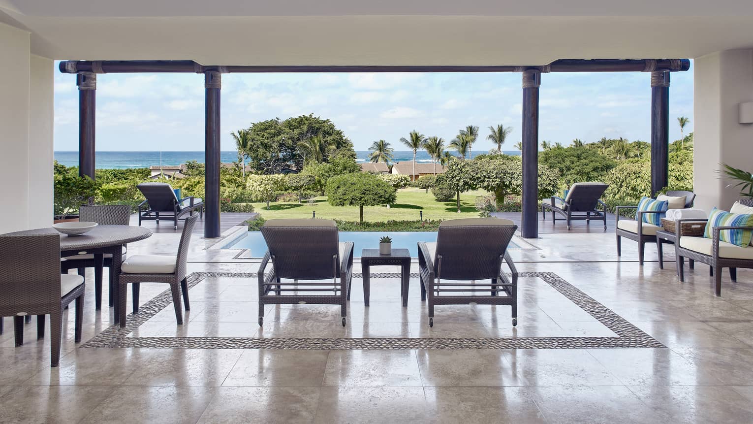 Terrace with dining table and lounge chairs, looking out to private pool and ocean in the distance