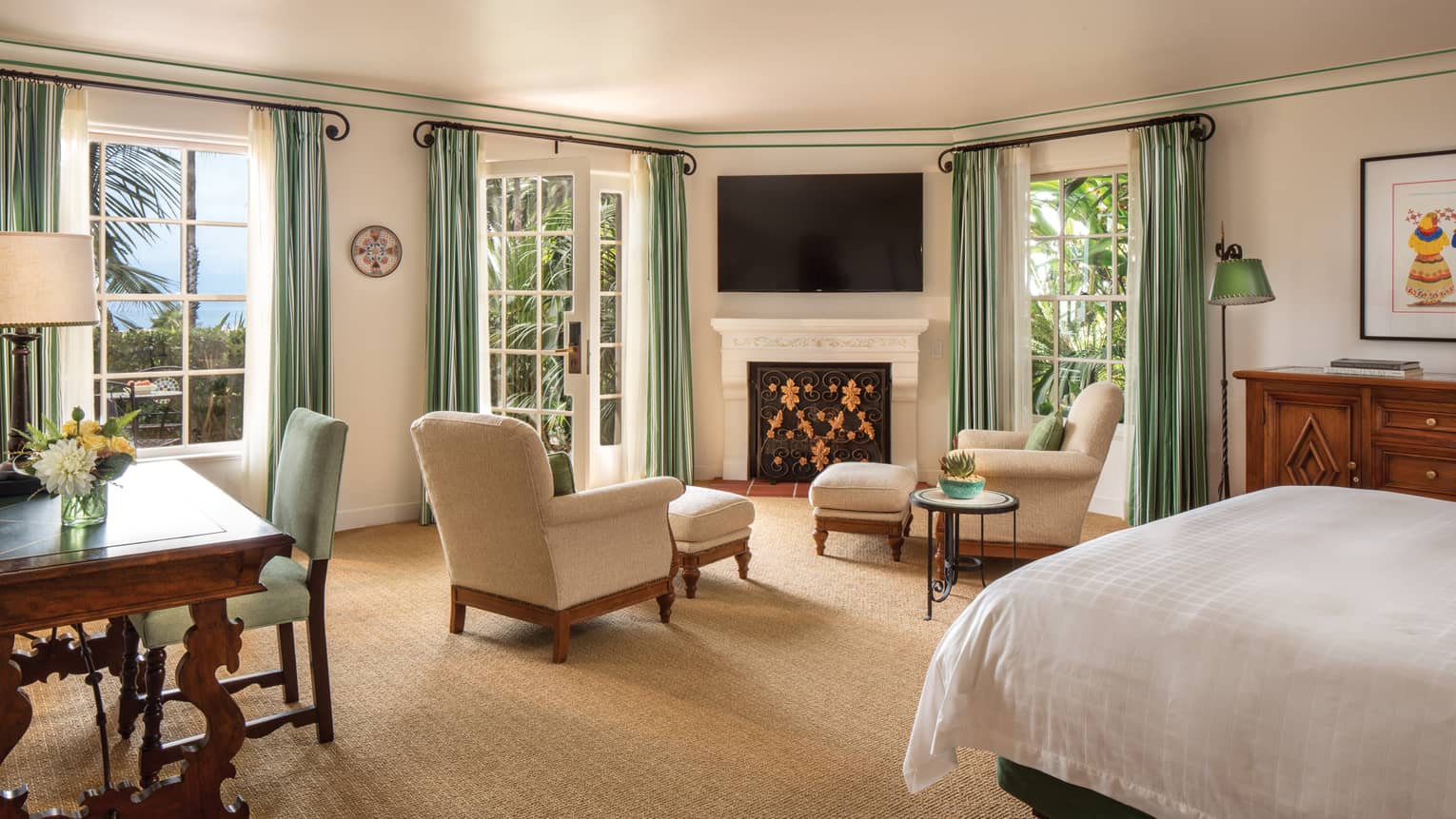 Ocean-View Room two white armchairs around fireplace mantle, TV, white French doors, green curtains