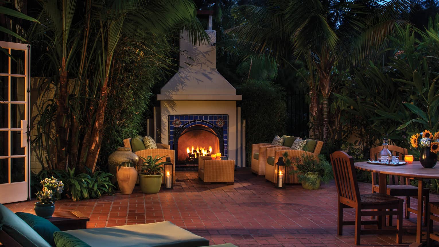 Fremont Bungalow tile patio with large stone outdoor fireplace, chairs, lounge chairs, dining table