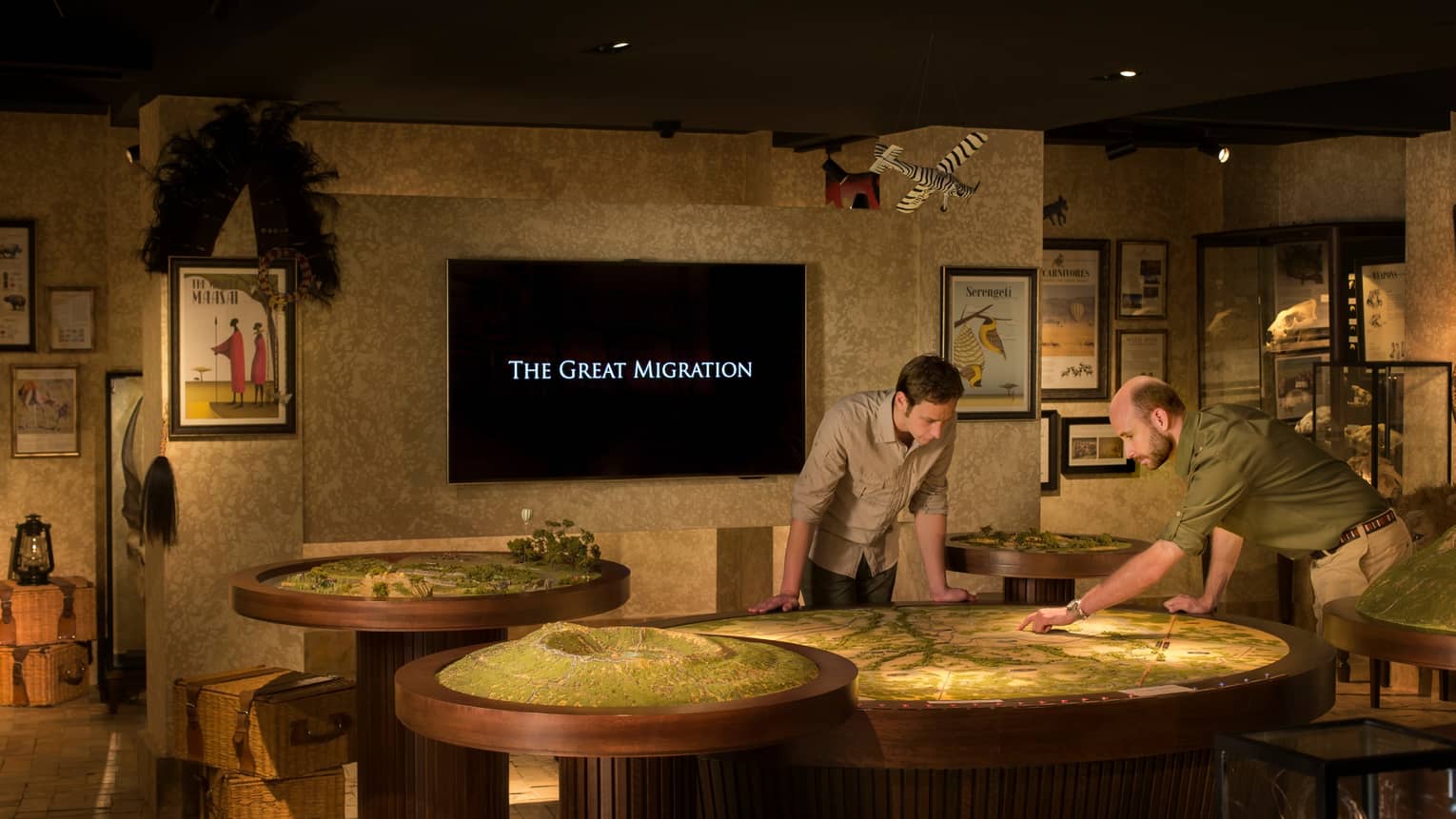 Two men examine model tables under screen reading The Great Migration