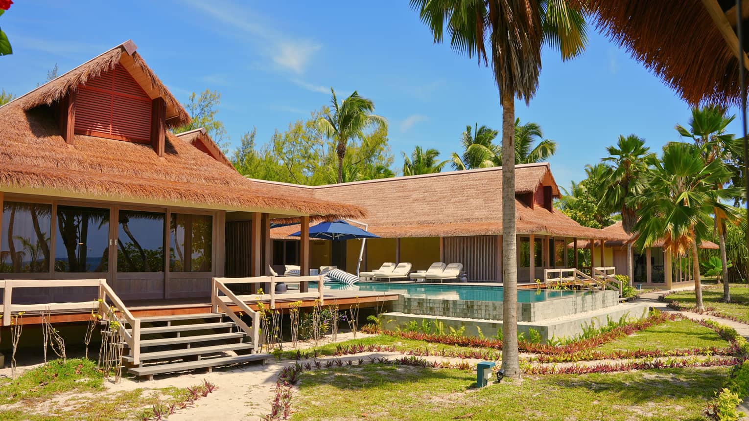 Large luxury residence at tropical resort, with thatched roofs and pool