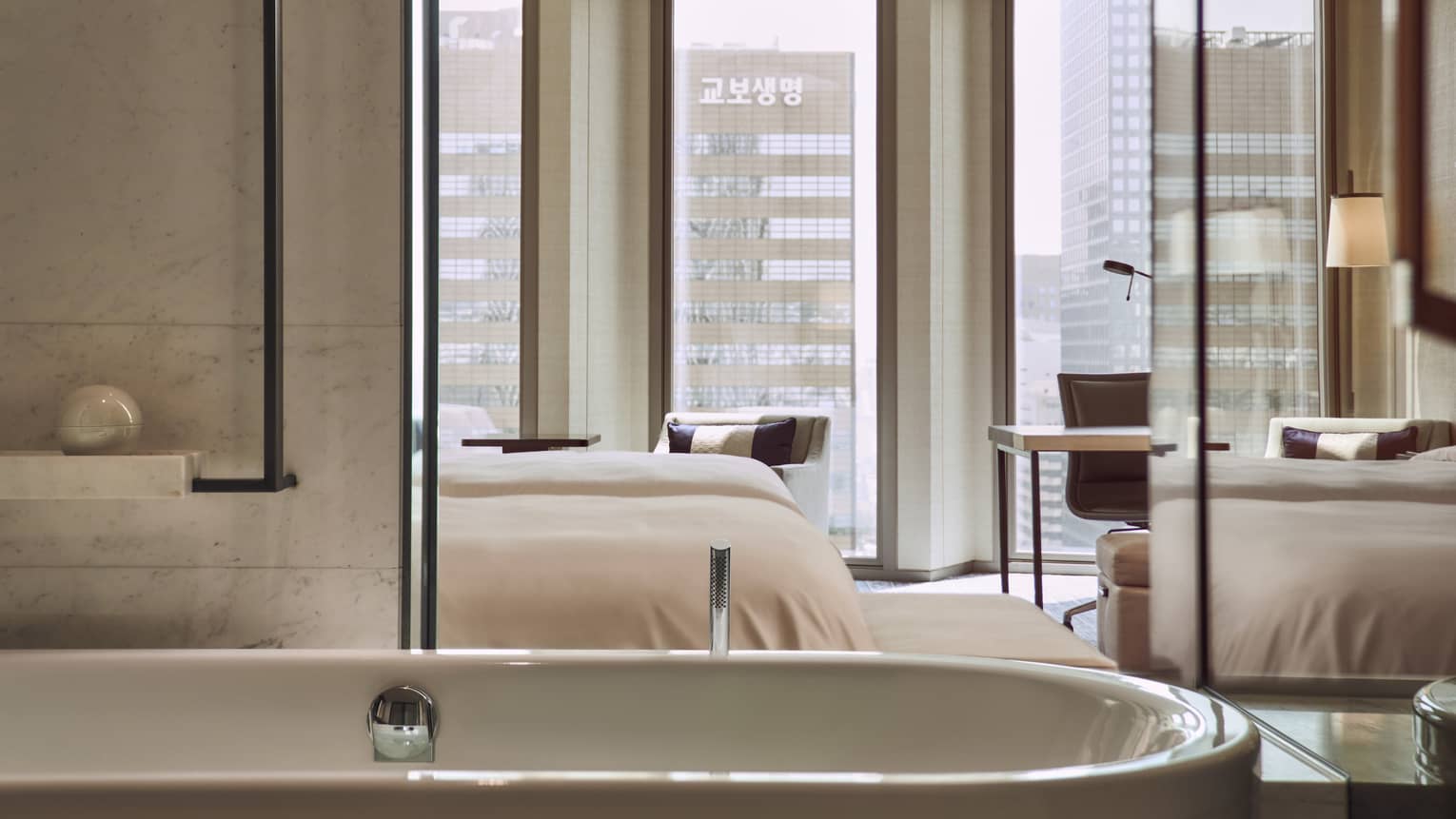 Modern hotel bathroom with deep soaking tub, opening to the bedroom with city views