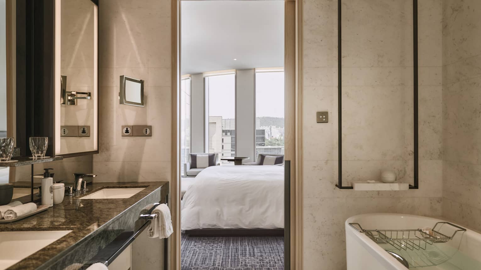 Hotel bathroom with deep soaking tub and double vanity, with view of bedroom