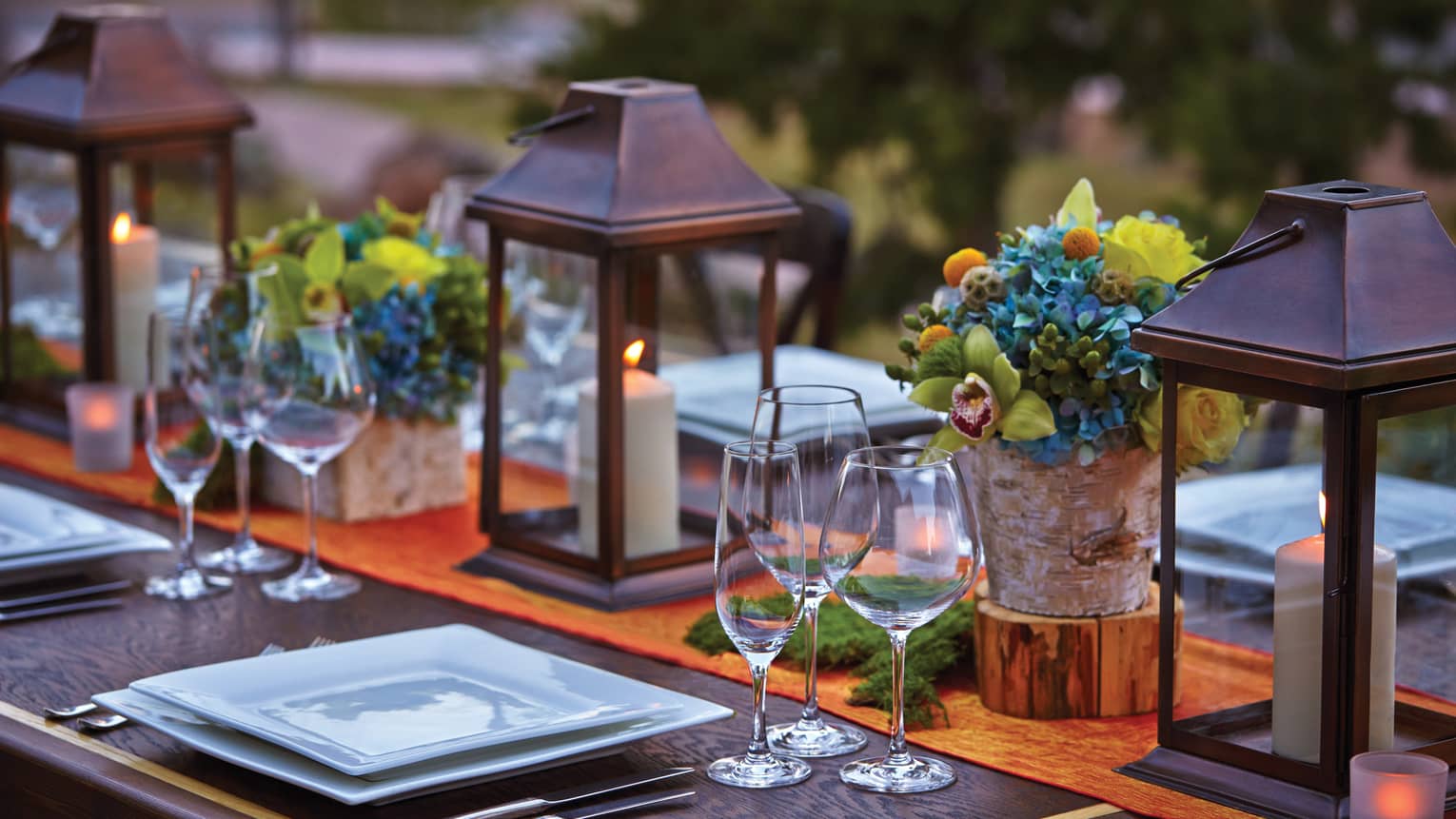 Close-up of lanterns, flowers on patio dining table at sunset