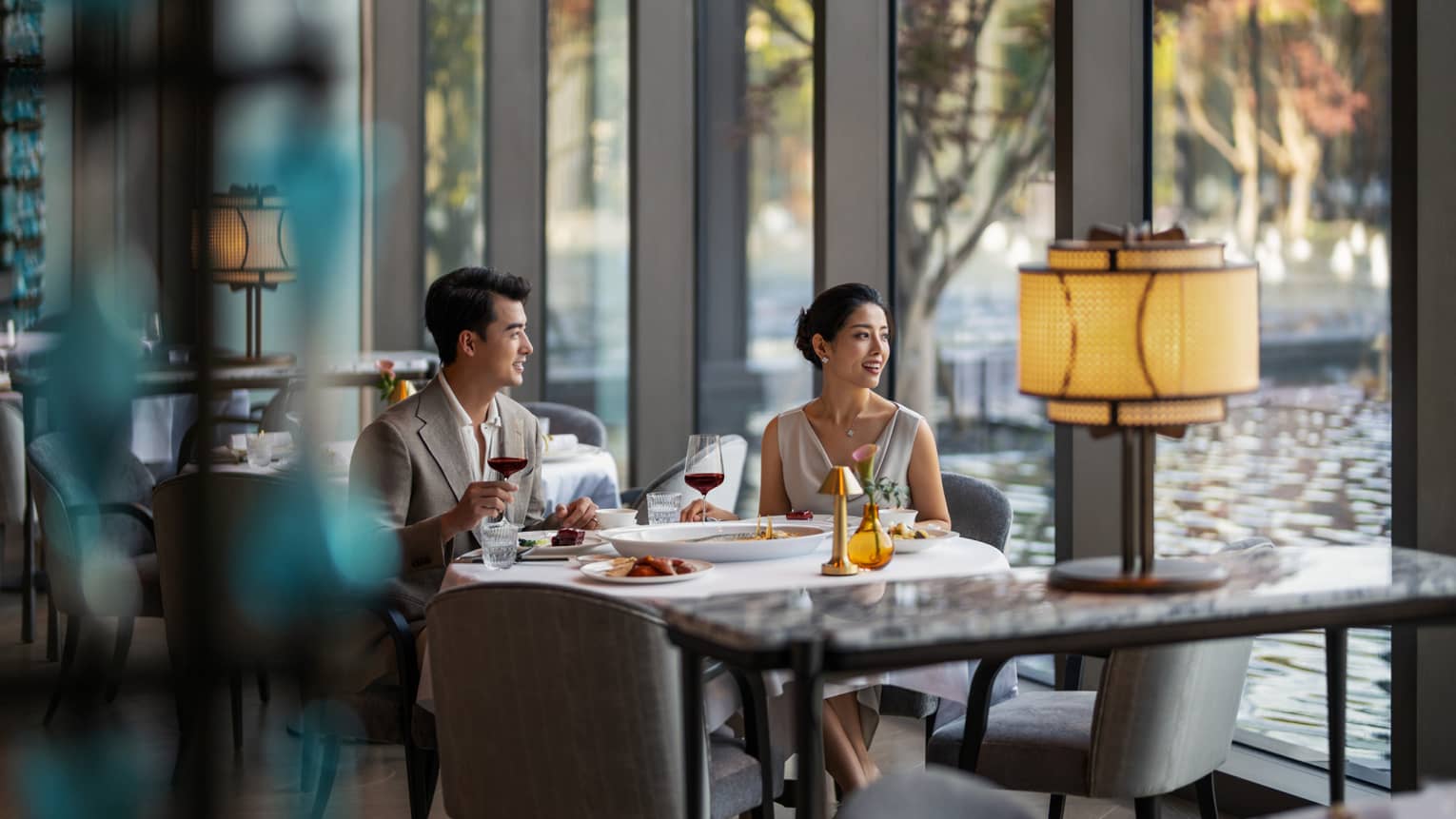 Man and woman dine at fine dining Chinese restaurant by the window with a pool view