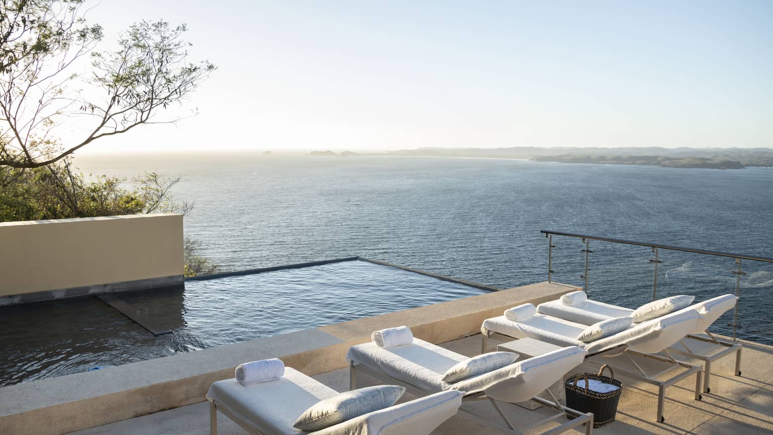 View of deck chairs, infinity pool and ocean beyond