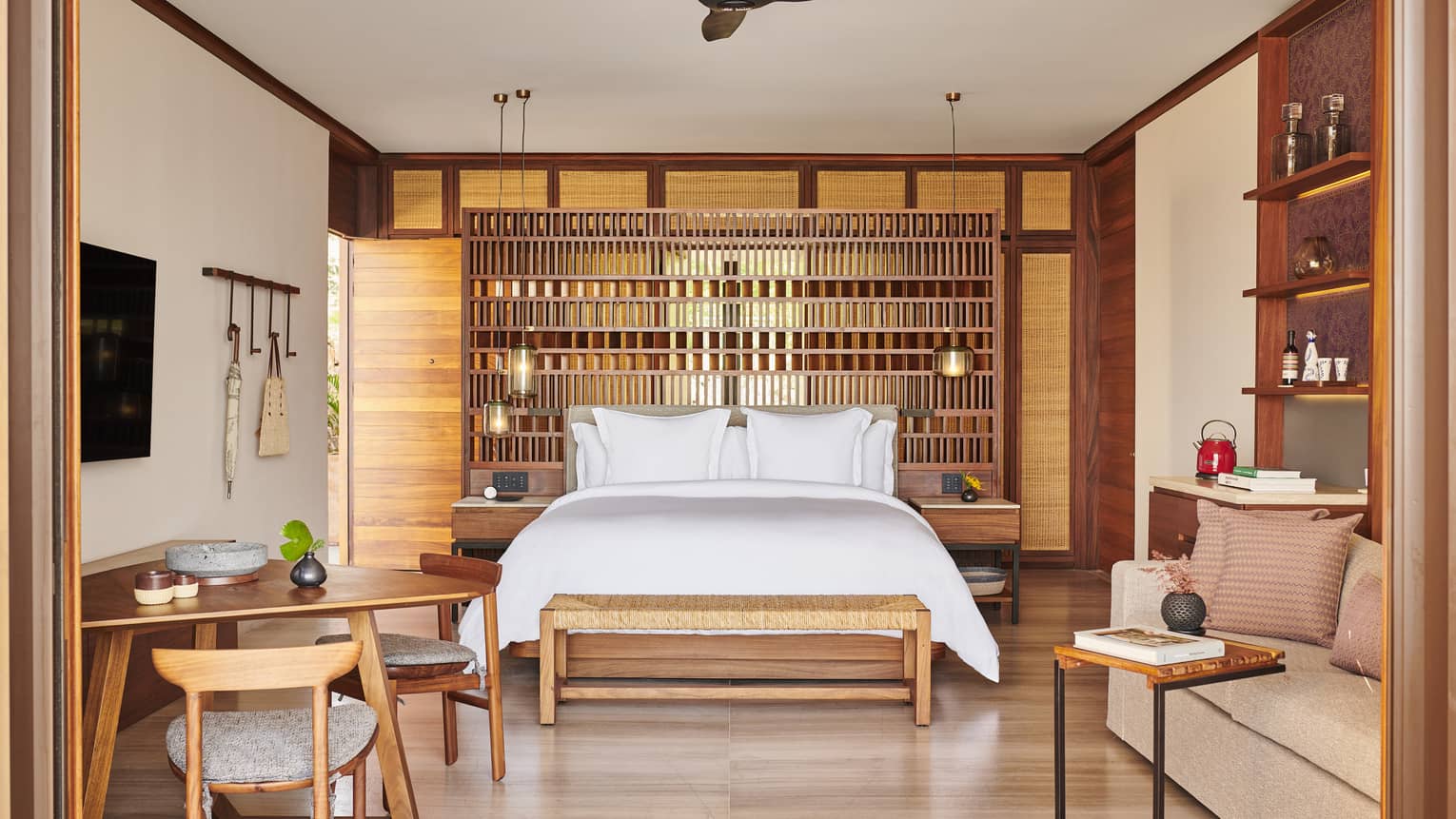 The interior of a beachfront room with a bed, shelves, small tables, chairs and sofa.