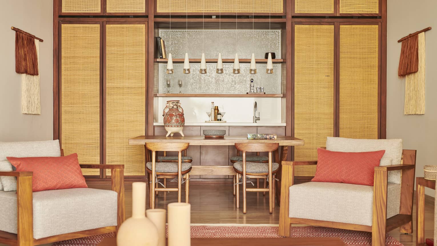 An interior of a suite with pink and warm colours, two chairs and a table with chairs.