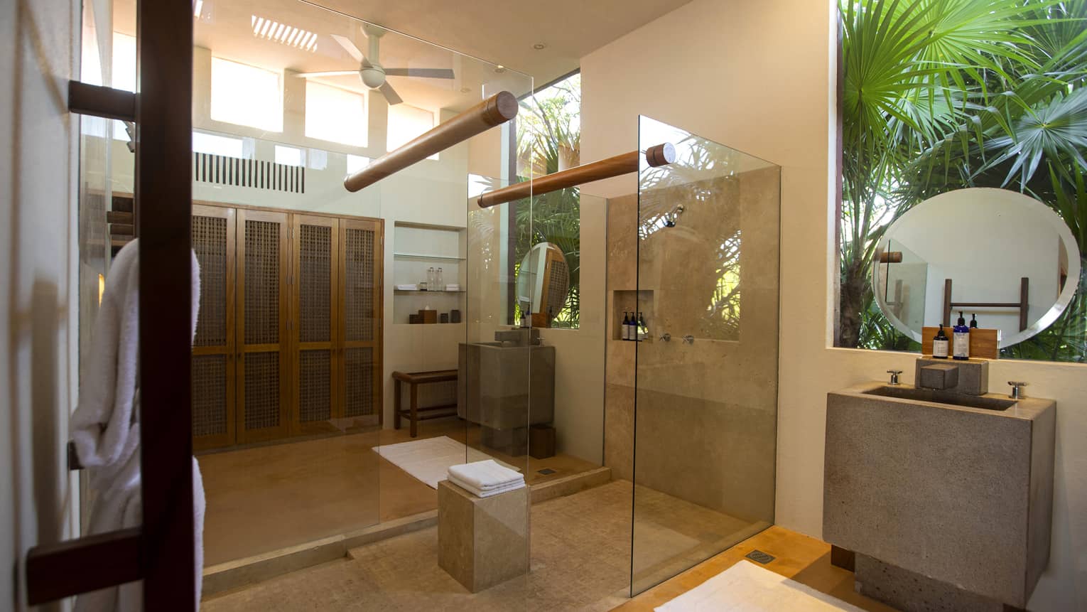 Large bathroom with walk-in shower and opening to the outdoors with palm trees