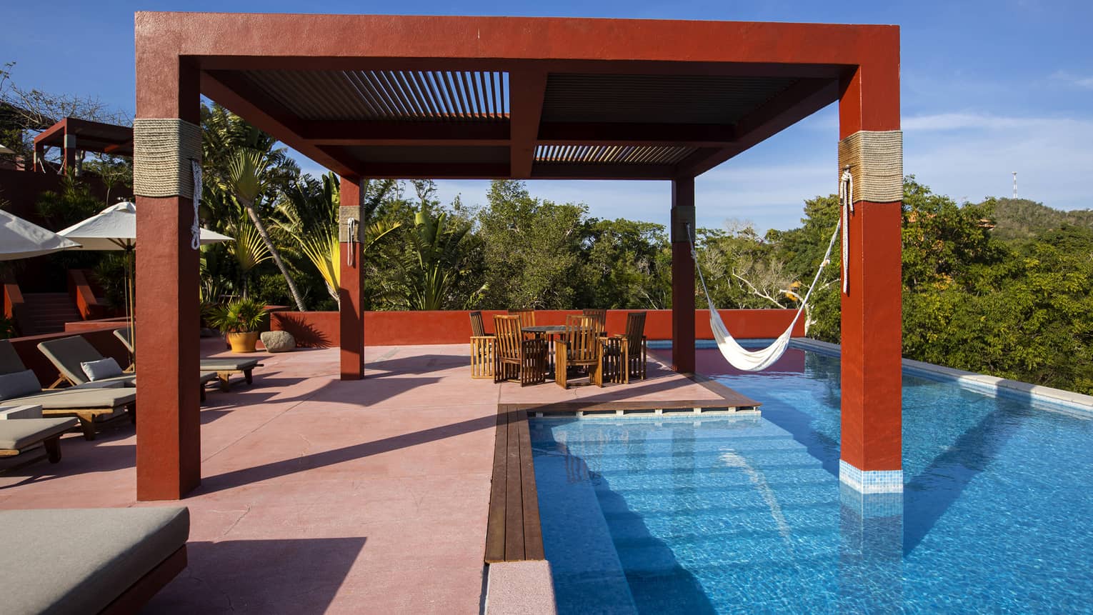 Red pergola over a pool deck and pool