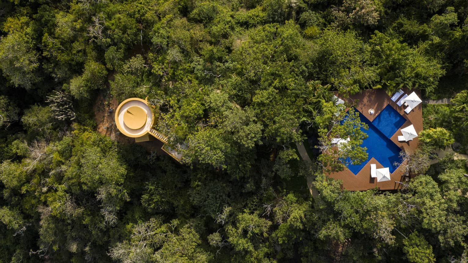 Aerial view of private villa and cross-shaped pool nestled within the jungle