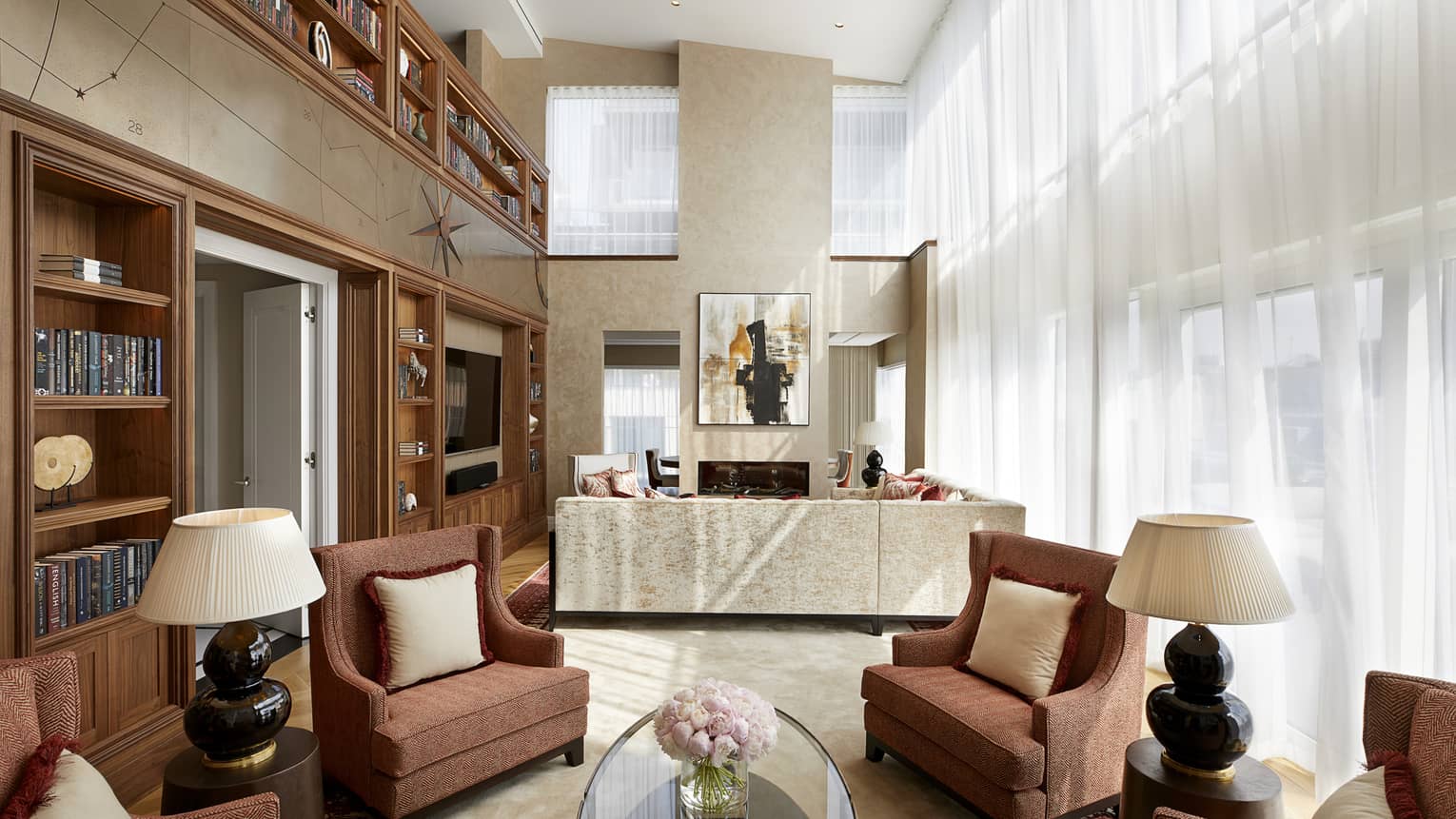 Armchairs, table and lamps under high loft ceilings in front of seating area, sofa