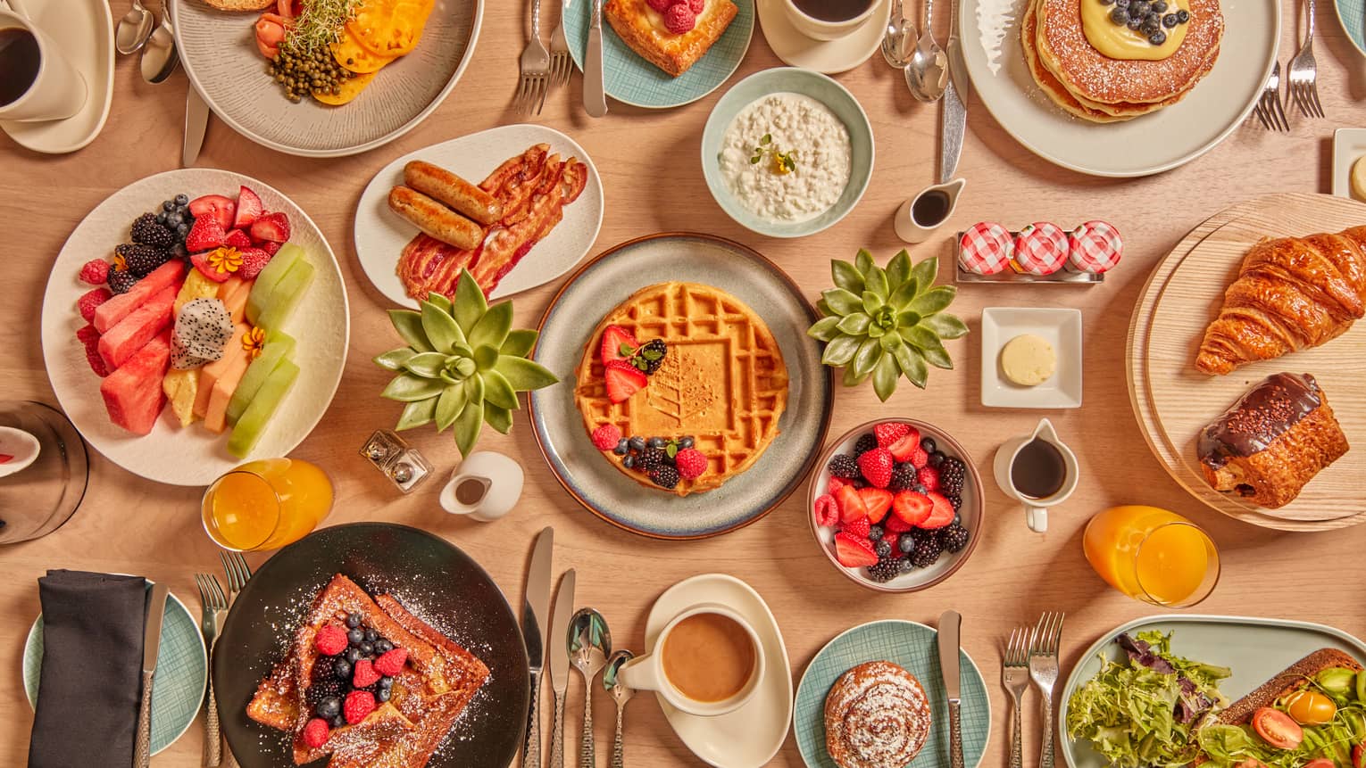 A large assortment of food on white, blue and other color plates.