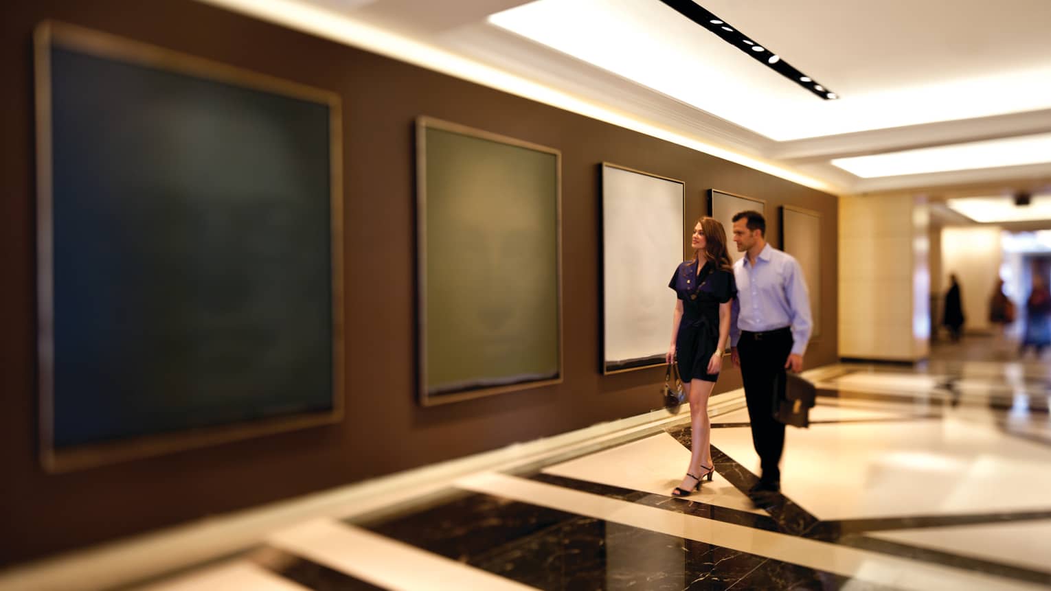 A man and woman walking through an art gallery.