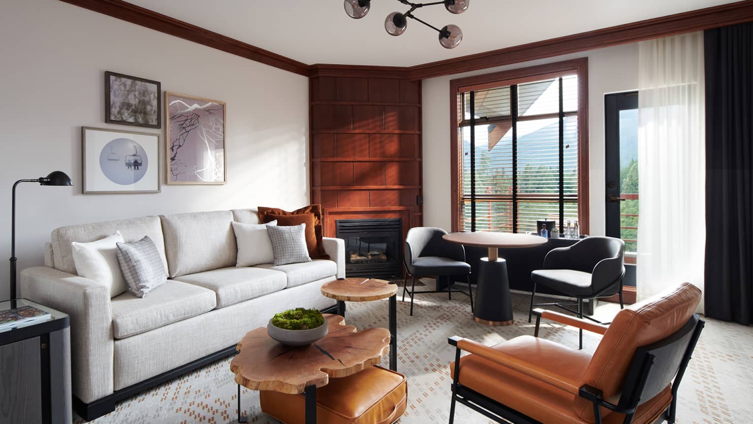 Chic and cozy Deluxe Suite at Four Seasons Whistler, showcasing a harmonious blend of contemporary and rustic elements. The living area is furnished with a sleek white sofa, tan leather chairs, a unique set of round wooden coffee tables, and a vintage-style leather suitcase used as a decorative piece. Wood-paneled walls and large windows offer views of the mountains, creating a luxurious yet inviting atmosphere. Artwork hangs above the sofa, adding a touch of elegance to the space.,Chic and cozy Deluxe Suite at Four Seasons Whistler, showcasing a harmonious blend of contemporary and rustic elements. The living area is furnished with a sleek white sofa, tan leather chairs, a unique set of round wooden coffee tables, and a vintage-style leather suitcase used as a decorative piece. Wood-paneled walls and large windows offer views of the mountains, creating a luxurious yet inviting atmosphere. Artwork hangs above the sofa, adding a touch of elegance to the space.