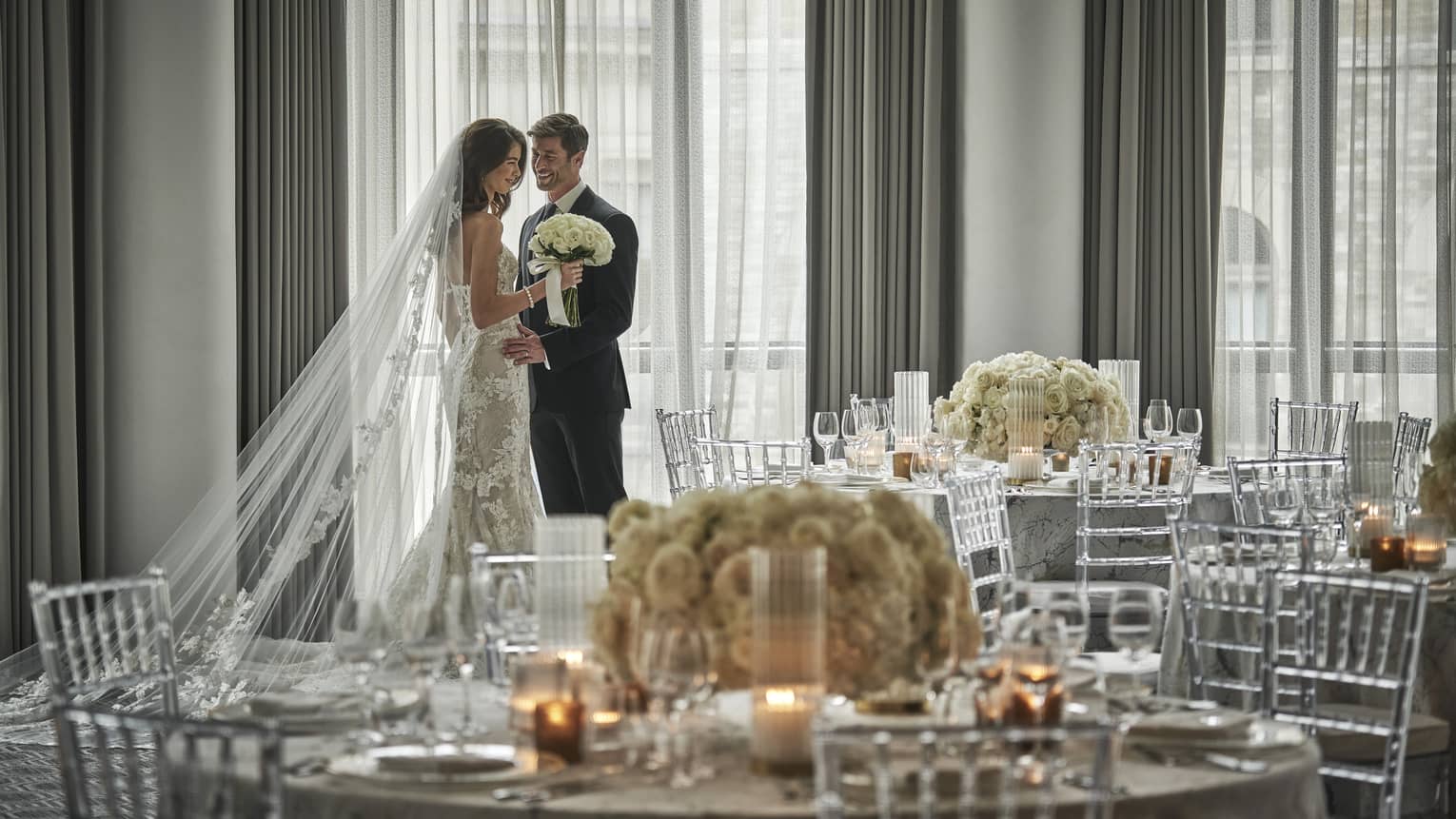 Bride and groom behind large round wedding banquet table with glowing candles