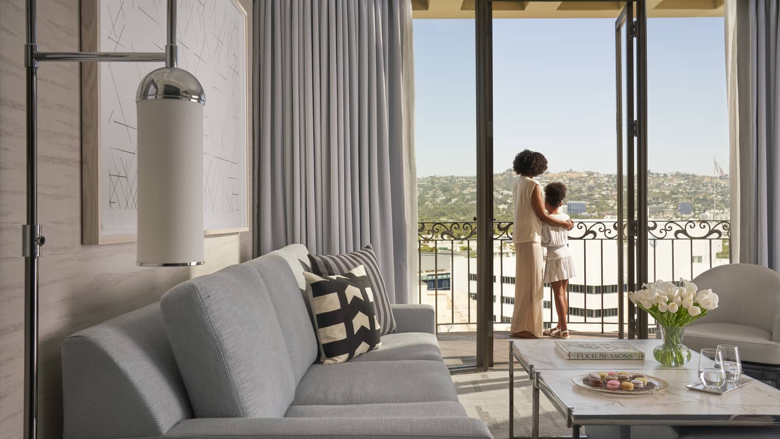 A mother and daughter looking out of a hotel window.