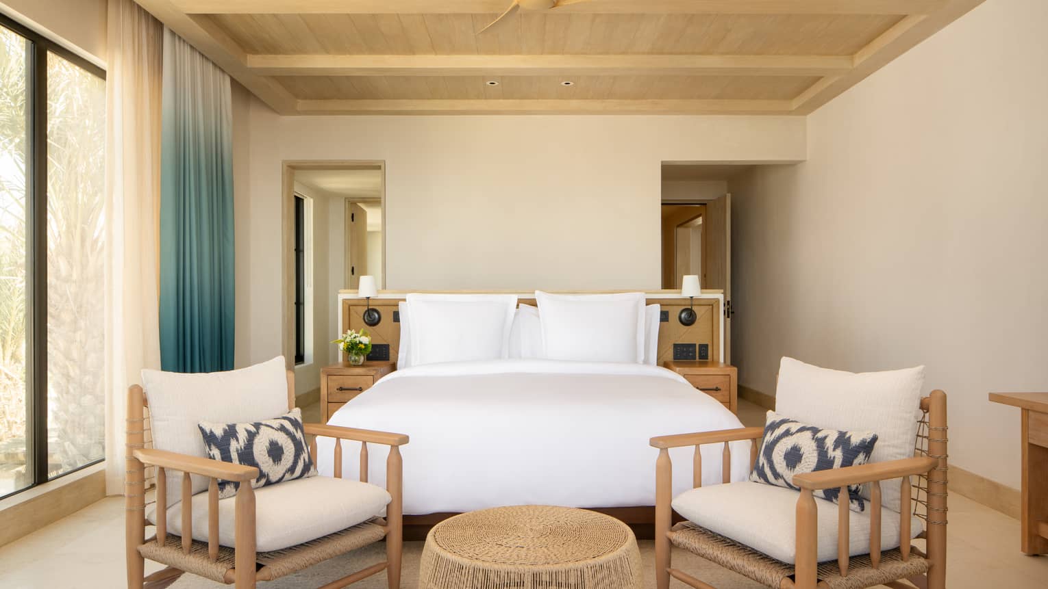 Luxury villa bedroom with king bed and two chairs, beamed ceiling, and windows, at Four Seasons Resort Cabo San Lucas at Cabo Del Sol