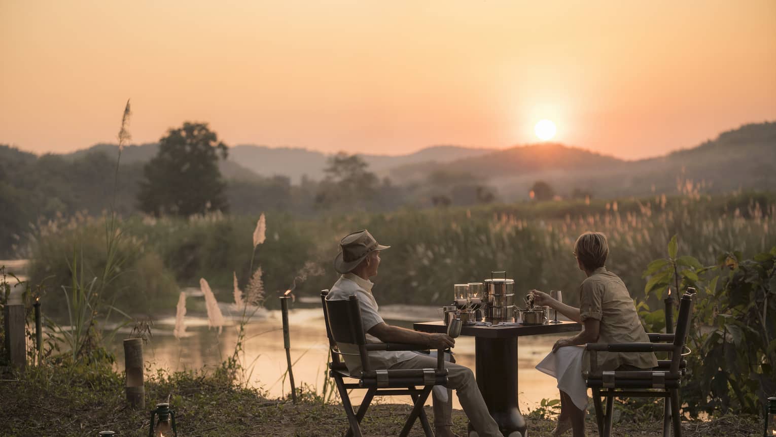 Couple enjoys Camp Bush Dinner along river at sunset