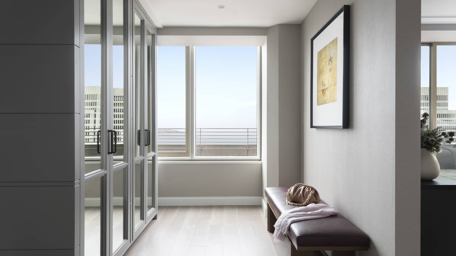 Hallway lined with mirrored closet doors; window at end