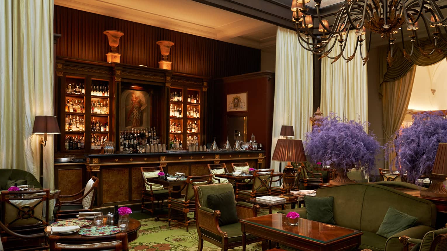 Elegant full mahogany lounge bar in the backdrop of cosy lounge seating in olive tones with purple flower accents