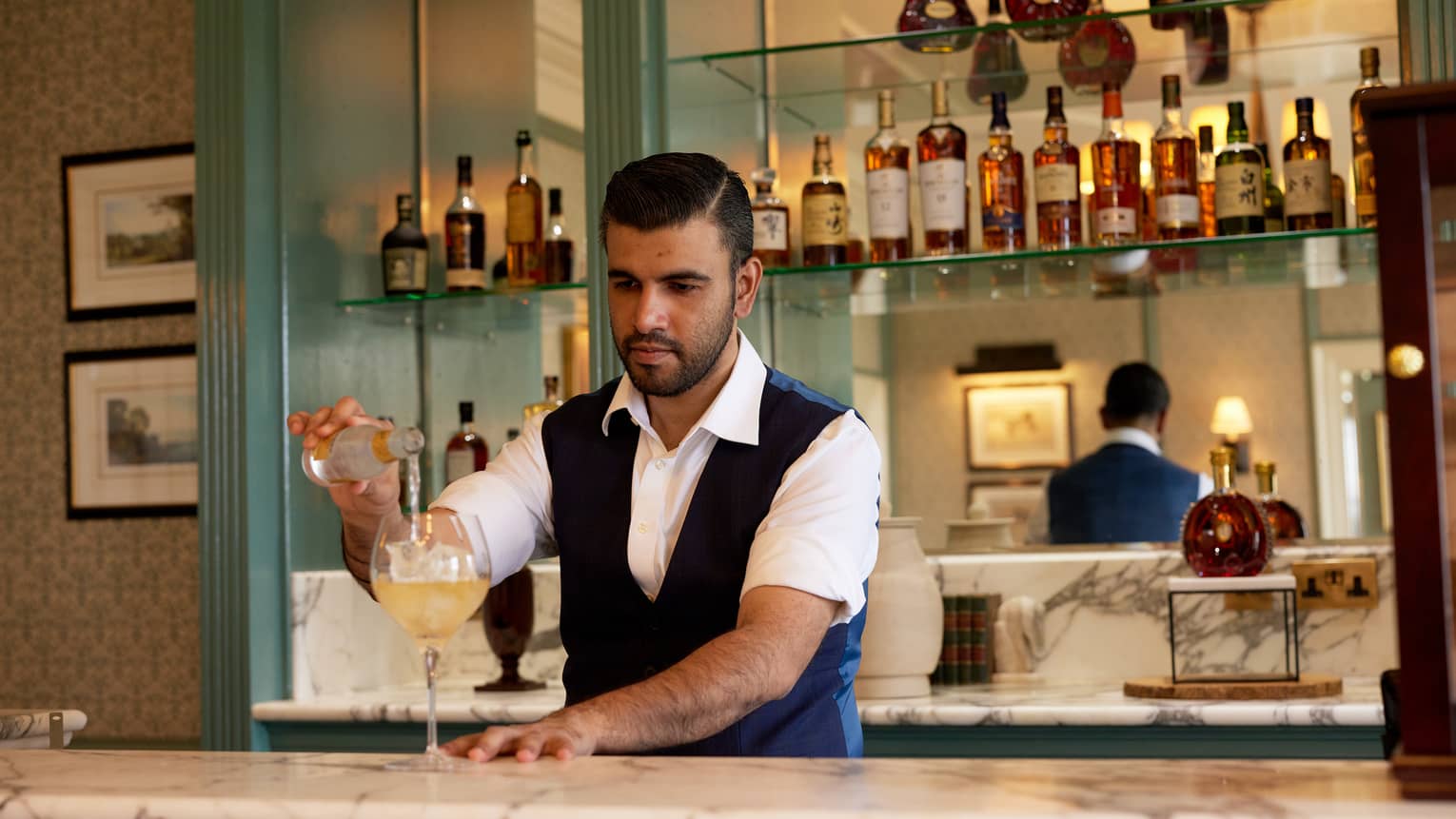 Bartender behind bar pouring a mixer into a cocktail