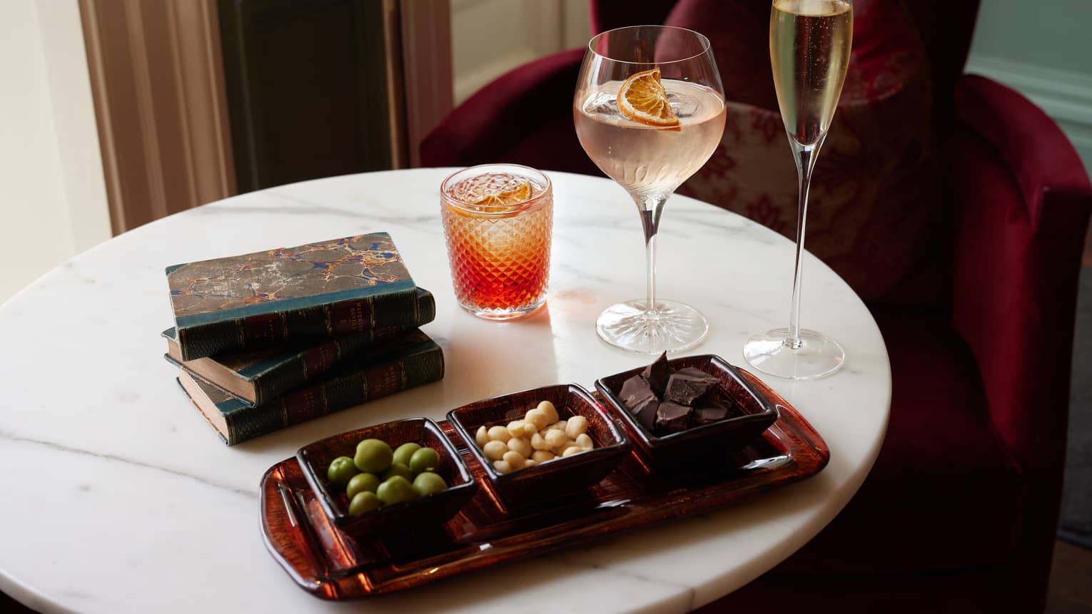 Bar snacks and three cocktails on round marble table