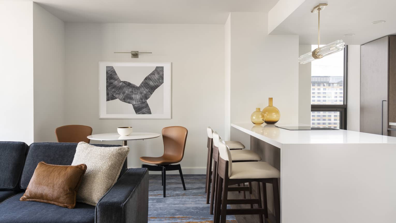 One-bedroom Residential Suite living area, dining area and kitchen with dark blue accents and bar stools