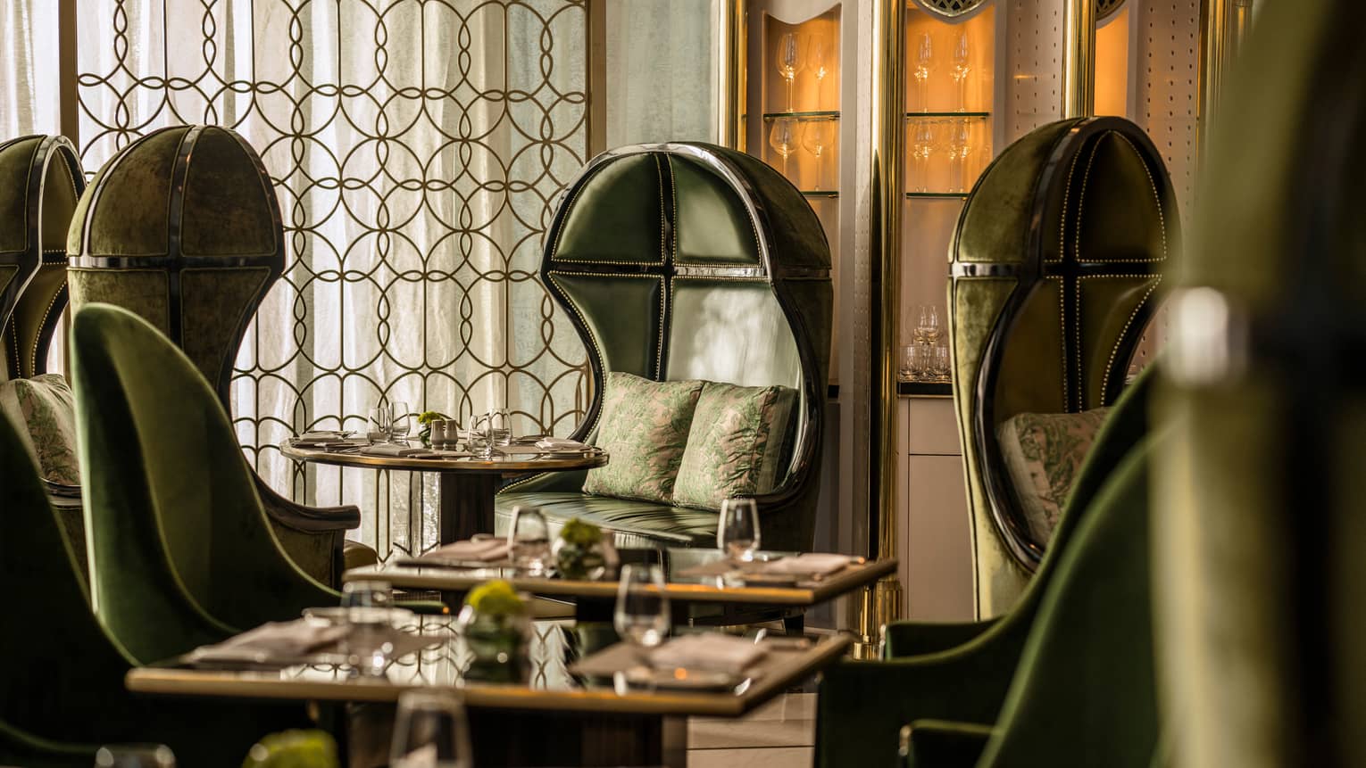 Premier Club booth with dark green leather bucket chairs, accent pillows, decorative brass screen