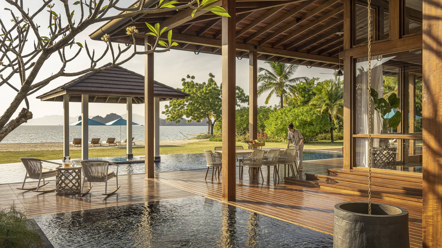 Private pool terrace and wooden deck under pergola, looking out to green lawn and Langkawi beach