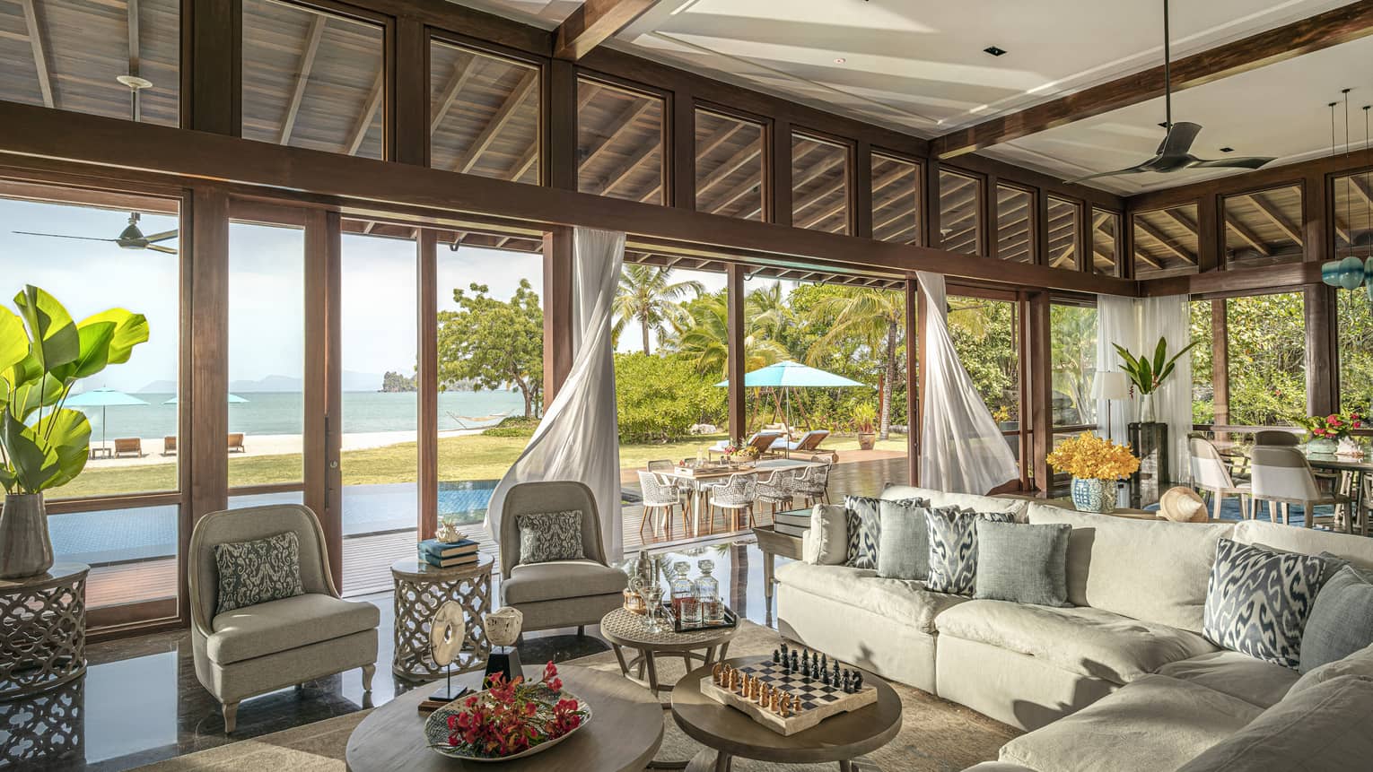 Large indoor-outdoor living room, opening up to beach view and pool terrace