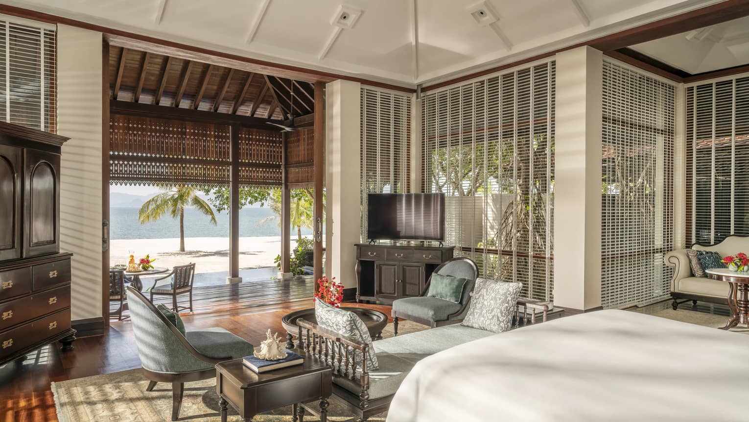 Bedroom with chaise and two arm chairs, plus opening to covered terrace and beach