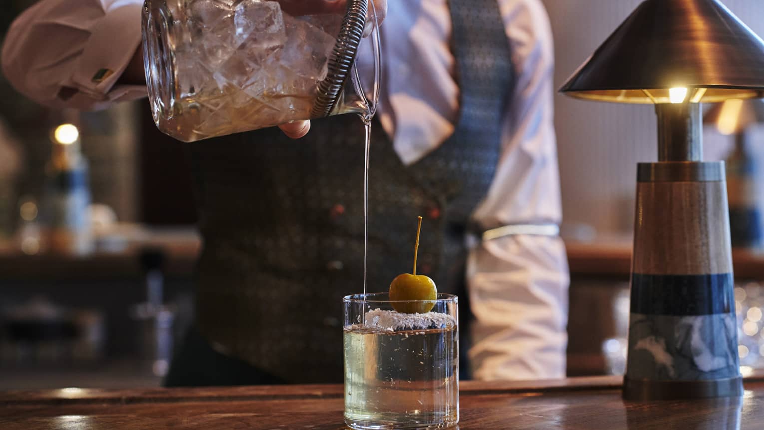A bartender pouring a drink into a glass.