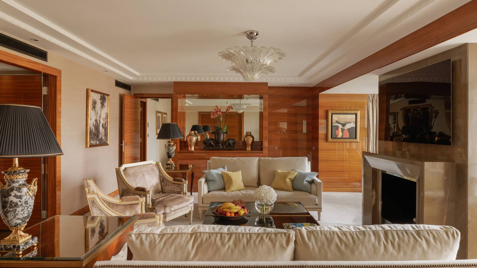 Elegant living room of Presidential Suite at Four Seasons Hotel London, featuring two sofas, two arm chairs, fireplace and TV