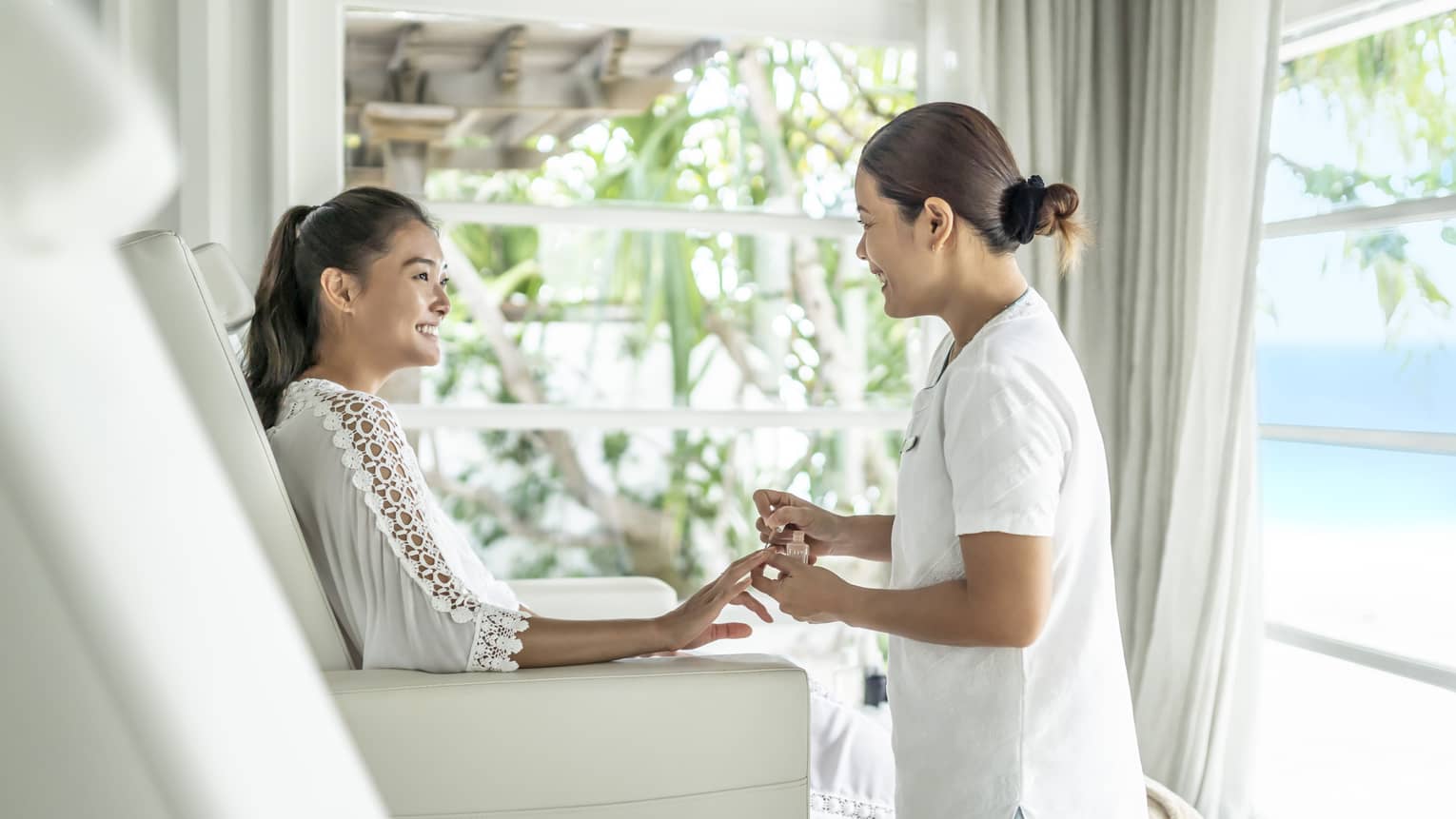A four seasons guest gets her nails down while sitting in a white leather salon chair 