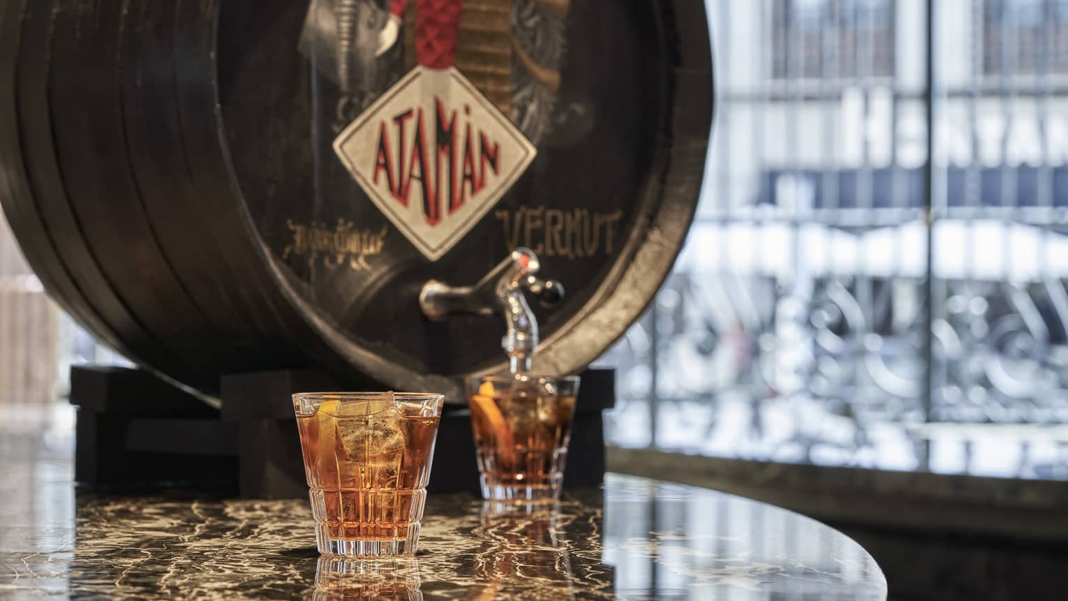 Vermouth cask with two filled cocktail glasses on marble table