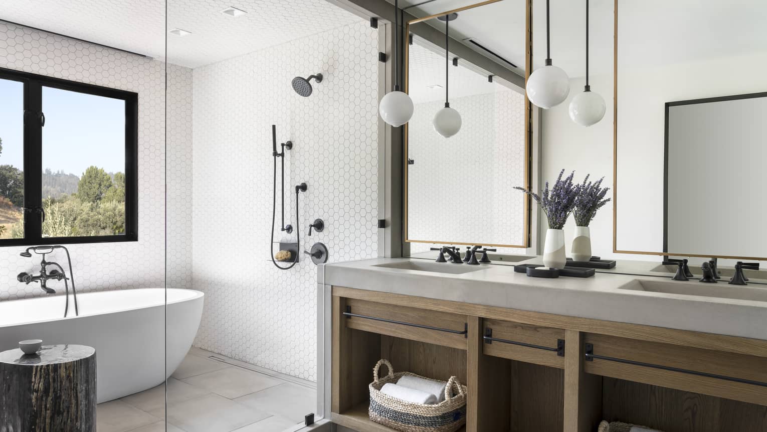 Bathroom with large grey and wood double vanity, oval tub, window
