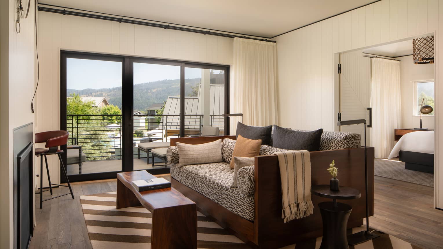 Contemporary living room with diagonal striped area rug, sofa, walk-out balcony and door to bedroom