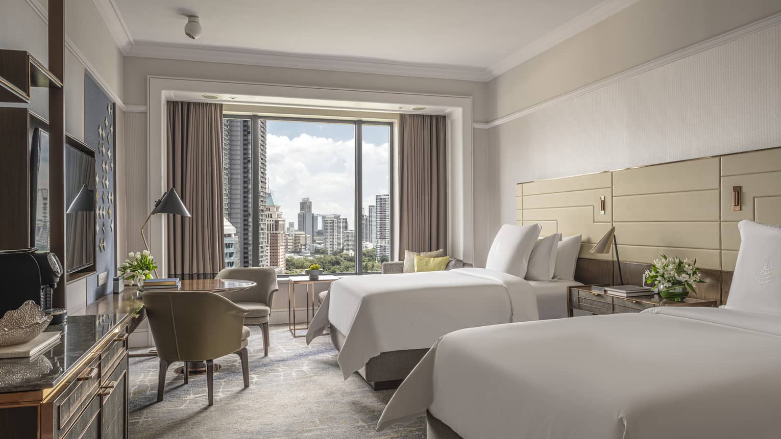 Hotel room with two twin beds, small table and two chairs, window of Singapore city