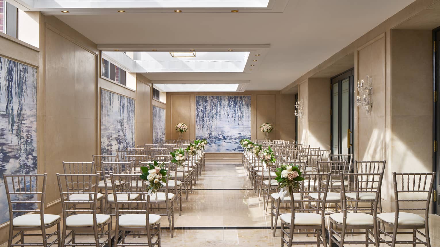 Rows of chairs under the ample skylights of Dumbarton Conservatory, decorated with wedding flowers.