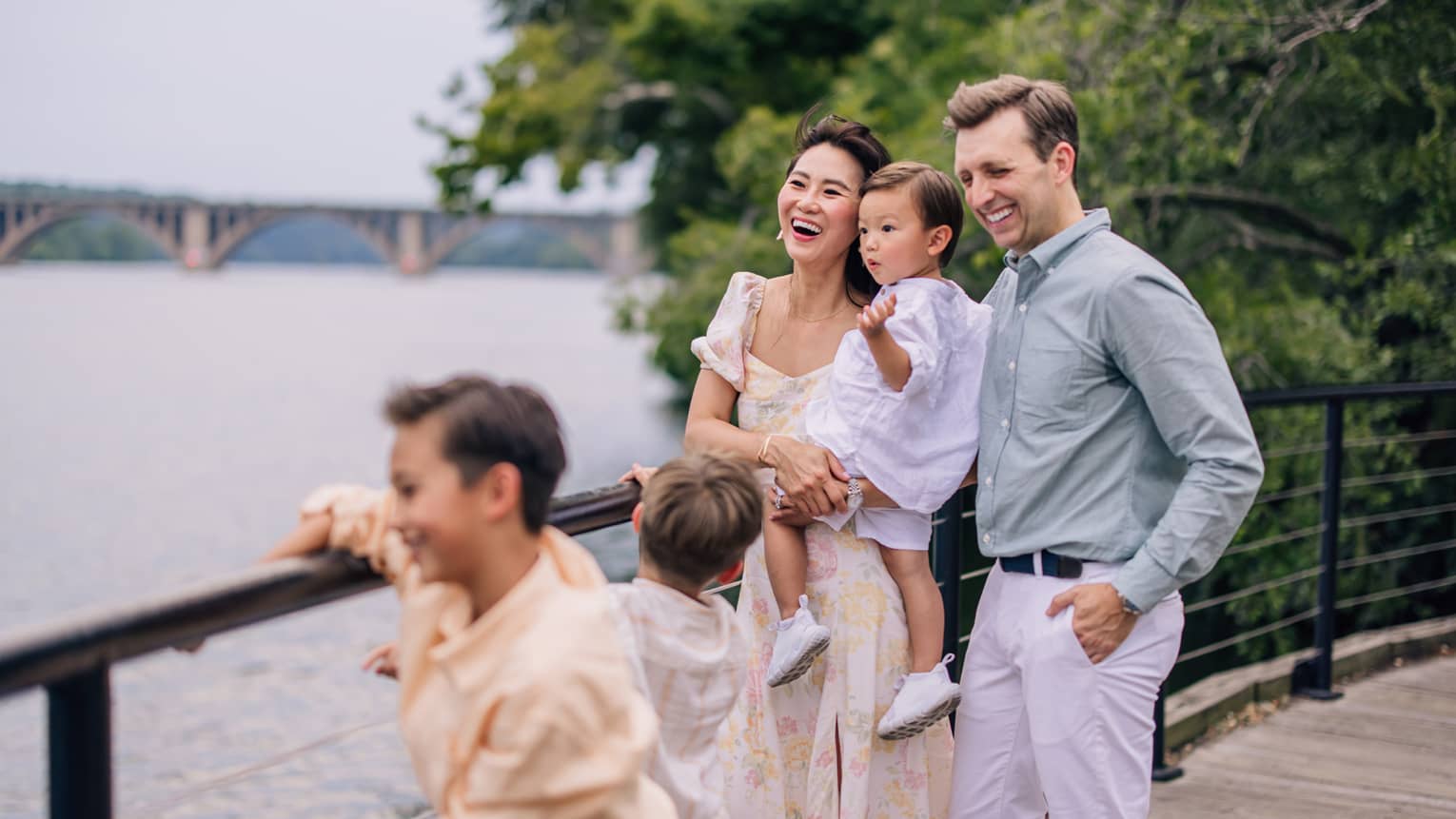 A man, woman, and three young children smile on a waterside path
