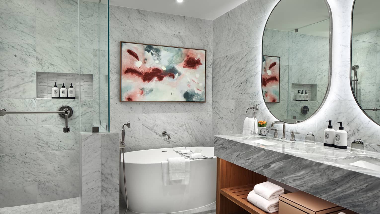 Marble bathroom with standalone tub and walk-in shower, as well as an illuminated double vanity