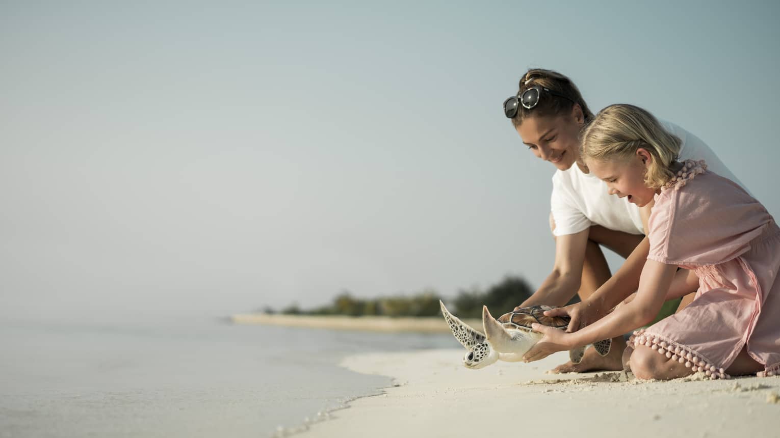 Marine Discovery Centre. Woman and daughter help release a sea turtle back in ocean