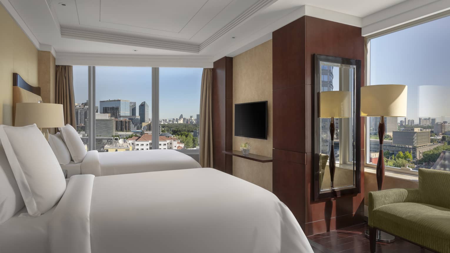 Hotel room with two single beds, windows on two walls, green love seat