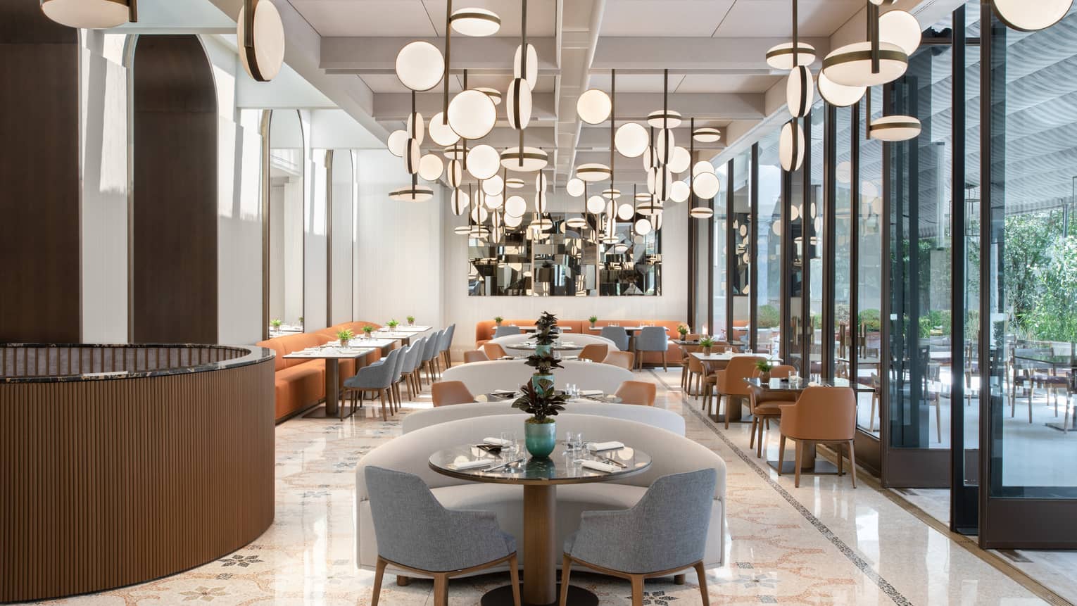 A cleanly decorated dining room with an array of unique lighting fixtures above