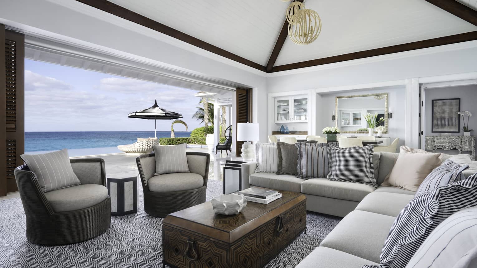 Beachfront Villa Residence large living room with modular sofa, armchairs by open wall to patio overlooking ocean  