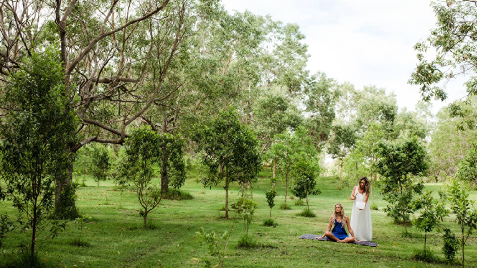 Two women in a garden-like setting of sandalwood trees